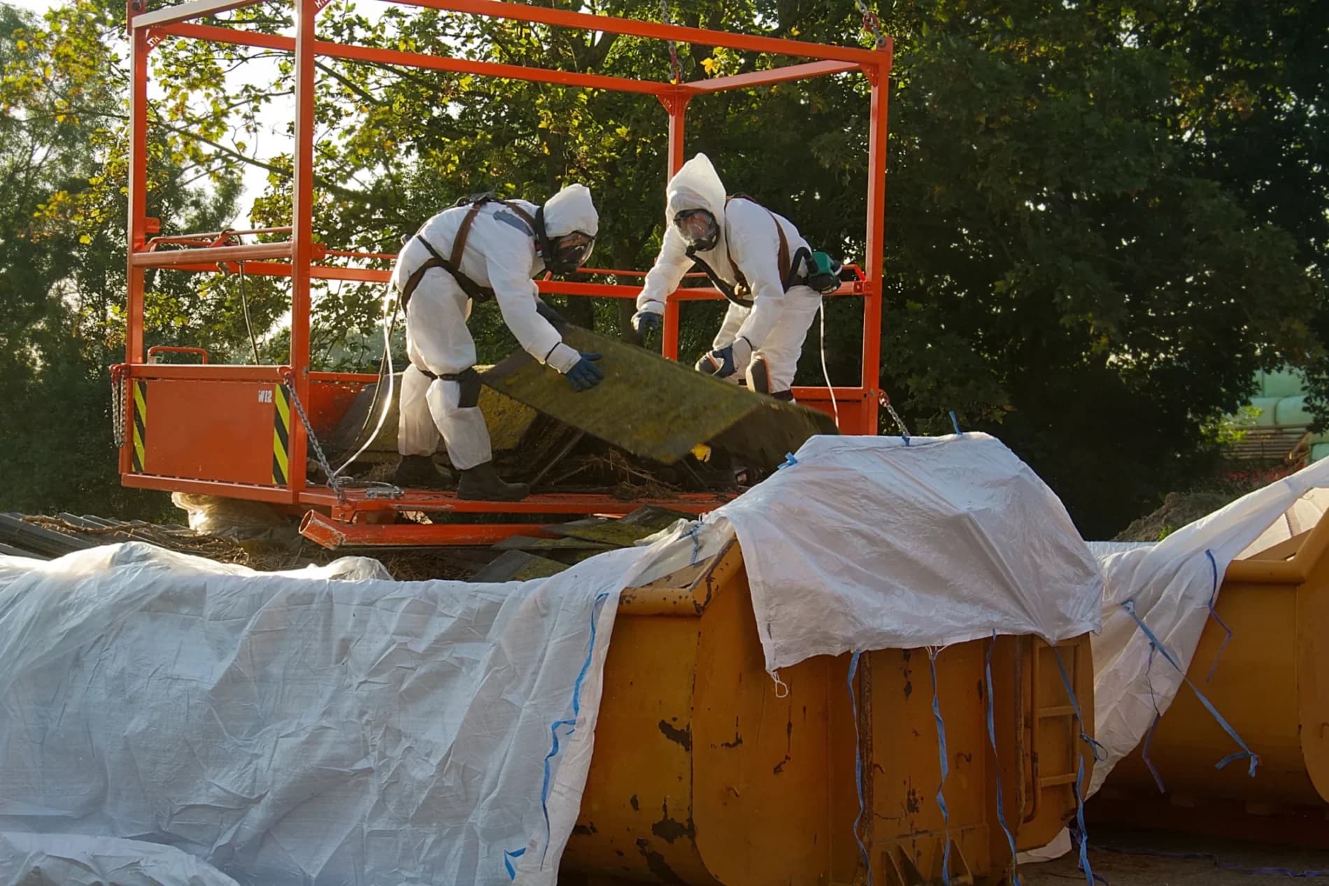 Workers in protective suits safely removing and bagging asbestos material