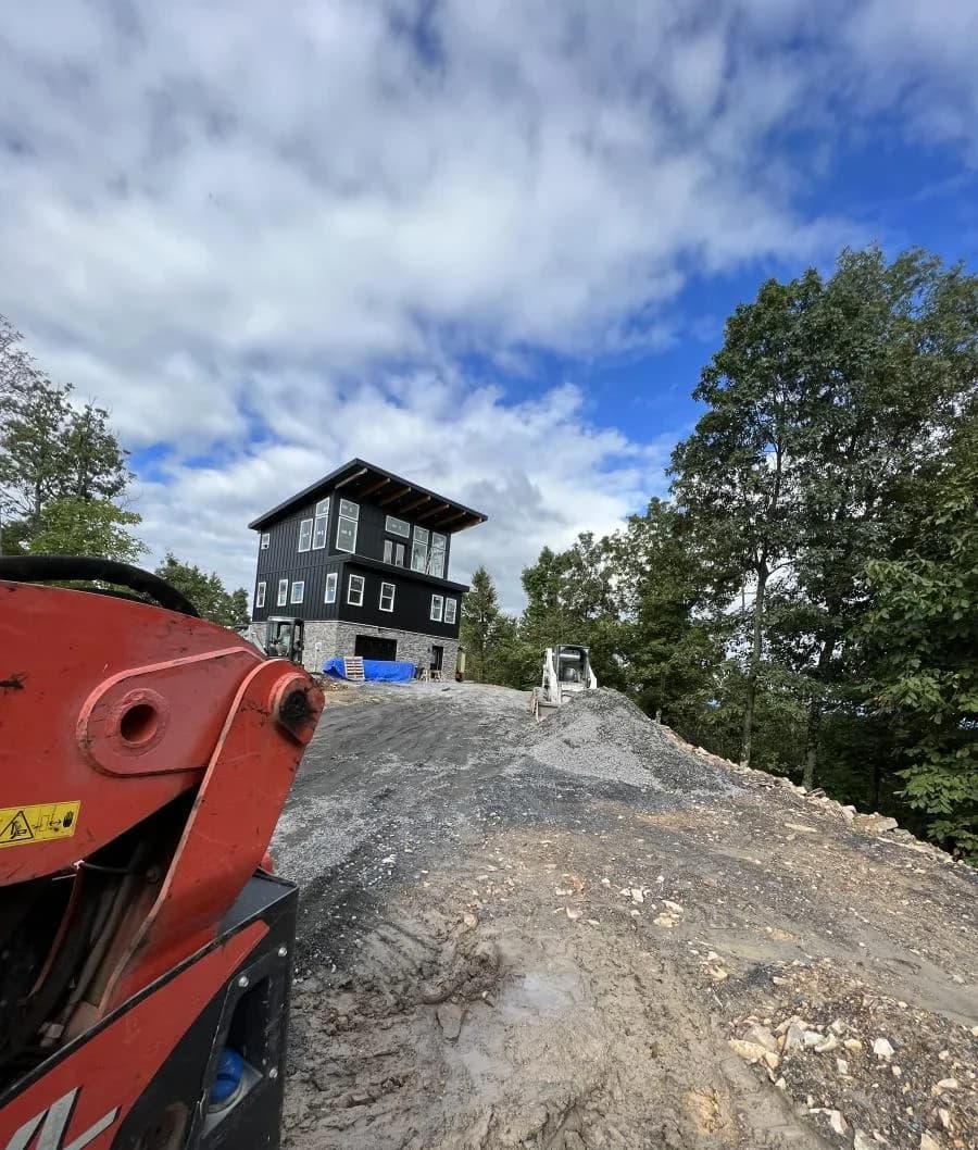 Compacted shale pad and access road with a skid steer on a hilltop build
